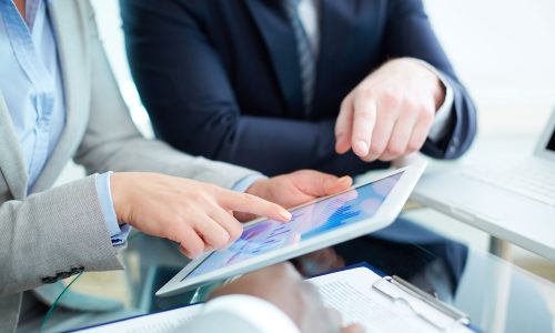 Image of human hands during discussion of business document in touchscreen at meeting